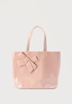 Pink patent tote bag with a textured bow accent, featuring two flat handles and gold branding on the front. Smooth, glossy finish.