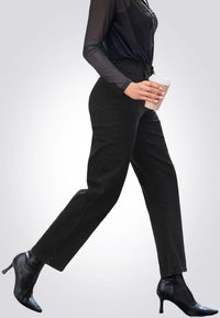 Jeans neri a vita alta a gamba dritta in denim, con tasche frontali e una trama liscia, abbinati a stivali neri con tacco alto.