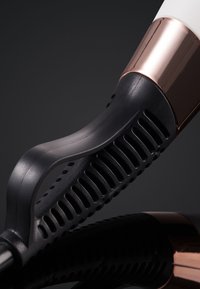 Gros plan sur un fer à friser noir et rose doré avec une poignée à ventilation et un design ergonomique incurvé sur une surface noire réfléchissante.