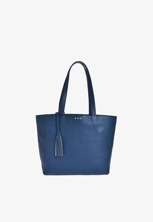 Sac cabas en cuir bleu marine avec deux bretelles et un pompon décoratif suspendu à une des bretelles.