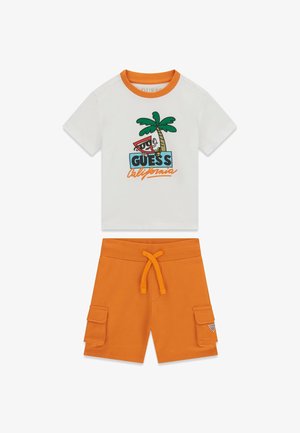 Bijela majica kratkih rukava s narančastim ovratnikom s crtanim slikama palme i tekstom "GUESS California", uparena s narančastim cargo šortsevima.