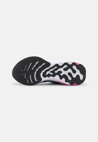 Semelle d'une chaussure de sport avec des motifs ondulés noirs et blancs et des accents roses sur fond blanc.