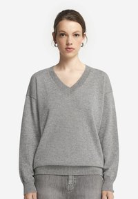 Szary dzianinowy sweter z dekoltem w serek, opadłymi ramionami i prążkowanym dołem. Miękka tekstura i luźny krój zapewniają komfort.