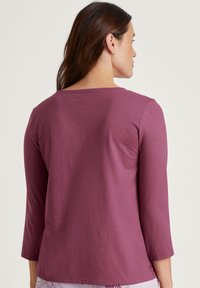 Aansluitend, langemouwen shirt in diep mauve, met een ruime halslijn en een zachte, gladde textuur met een relaxte pasvorm.