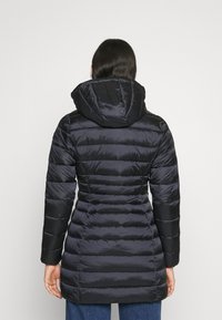 Oppustet sort jakke med hætte, præget af vandrette syninger, glat tekstur og en tætsiddende silhuet. Bagfra ses lange ærmer.