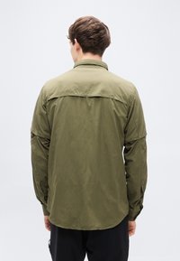 Πουκάμισο κουμπωτό σε ελαιί πράσινο χρώμα με μακριά μανίκια, με ομαλή υφή και στρογγυλεμένη βάση, εμφανιζόμενο από πίσω με έναν απλό γιακά.