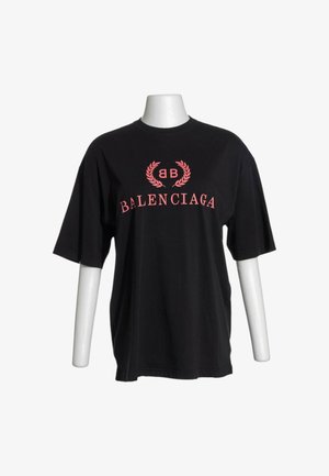 Schwarzes T-Shirt mit kurzen Ärmeln mit pinkem "BB" Lorbeer-Logo über pinkem "BALENCIAGA" Text vorne, dargestellt auf einem weißen Schaufensterpuppe-Torso.