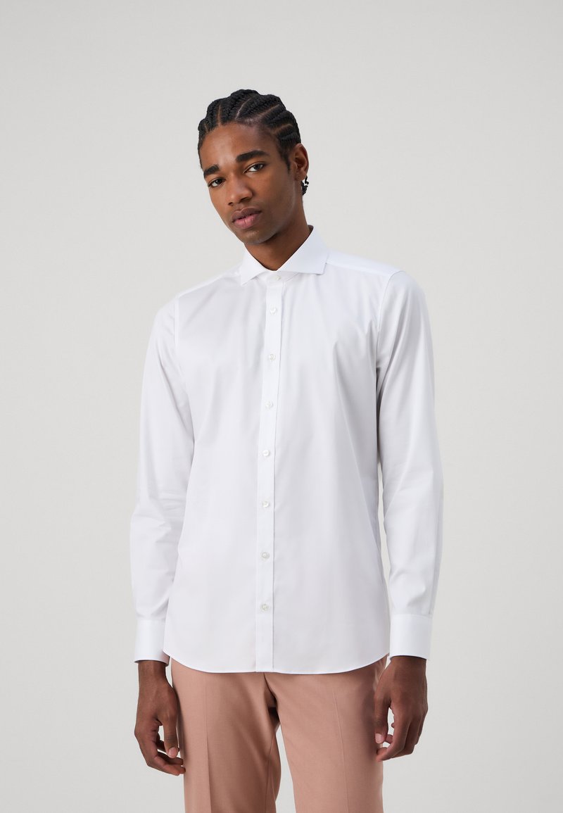 White long-sleeve button-up shirt with a collar, smooth fabric, and a rounded hem, paired with pale pink trousers.