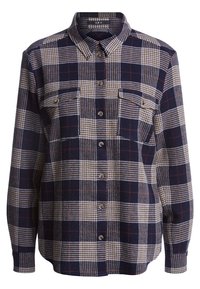 Chemise à carreaux à manches longues et boutonnée en marine, beige et marron, avec deux poches poitrine et un col pointu.