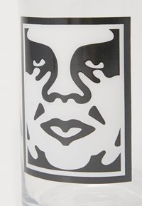 Clear glass tumbler featuring a black and white design of a stylized face, outlined within a square, with prominent features and abstract details.