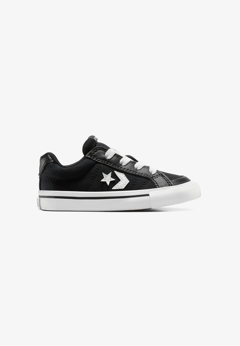Zapatillas de lona negras con acentos blancos, con un diseño de estrella y flecha, punta redonda y cierre con cordones. Suela de goma con agarre texturizado.