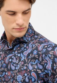 Donker patroon shirt met paisley ontwerpen in blauw, rood en beige. Knopsluiting kraag en textuur stof met bloemaccenten.