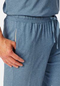 Helle blaue Jogginghosen aus weichem, dehnbarem Stoff. Sie verfügen über einen elastischen Bund mit Kordelzug, seitliche Taschen und eine lässige Passform.