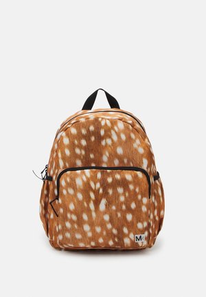 Sac à dos marron avec des taches blanches ressemblant à celles d’un cerf, poche avant zippée, tirettes de fermeture éclair noires et boucle de poignée supérieure noire sur fond uni.