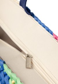 Geweven, multikleurige tas met blauwe, roze en groene accenten, een crèmekleurige binnenkant en een zilveren ritsluiting.