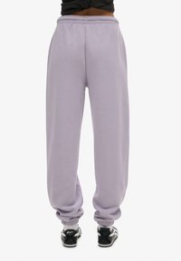 Lavendel joggingsbroek met elastische tailleband en boorden, met een ontspannen pasvorm en zachte textuur. De achterkant toont geen extra details.