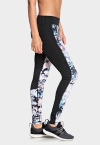 Černé legíny s vysokým pasem, zdobené barevnými květinovými bočními panely, vyrobené z pružného materiálu, s bezpečným pasem a boční kapsou.