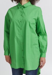 Green long-sleeve button-up shirt made of lightweight fabric, featuring a collared neckline, cuffed sleeves, and a slightly curved hem.