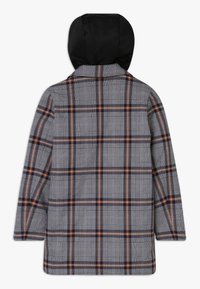 Abrigo de cuadros de manga larga con capucha negra, que presenta un patrón de cuadros en gris, azul marino y naranja óxido, mostrado desde la parte posterior.
