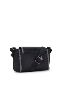 Černá crossbody taška vyrobená z odolné tkaniny, se zvýrazněným bílým šitím podél okrajů a nastavitelným popruhem s kovovými stříbrnými detaily.
