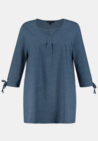 Blå, långärmad tunika med V-hals, med detaljer i veck och knytningar vid ärmsluten, tillverkad av ett mjukt, texturerat tyg.