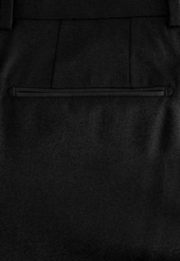 Black fabric pants featuring a smooth texture, single zippered back pocket, and tailored stitching for a fitted appearance.