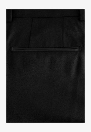 Pantalons en tissu noir avec une texture douce, une poche arrière zippée et des coutures sur mesure pour un aspect ajusté.
