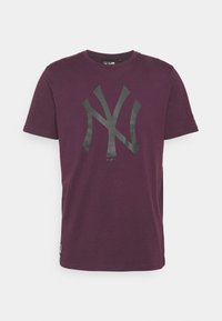 Lila bomullströja med korta ärmar och rund halsringning. Har en stor svart NY-logga på framsidan. Standard passform.