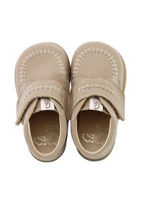 Zapatos infantiles beige con upper de cuero suave, cinta de velcro y costuras blancas contrastantes. Punta redondeada y forros interiores acolchados.