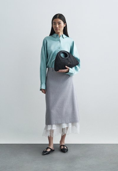Chemisier à manches longues bleu clair, jupe crayon grise, sac à main noir tissé avec une poignée ronde, ballerines noires texturées, détail en dentelle superposée en bas.