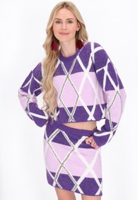 Violeta un rozā cropped džemperis ar ģeometrisku dimanta rakstu, kombinēts ar atbilstošu svārku; maiga tekstūra ar baltām un sudraba akcentiem.