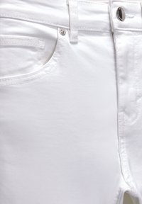 Vaqueros de mezclilla blanca con una textura suave, detalles de costura sutil, cierre de botón plateado y abertura de bolsillo en la parte delantera.