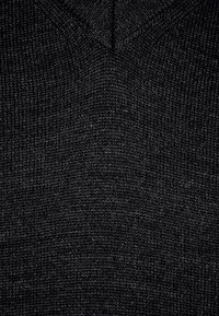 Schwarzer Strickpullover mit V-Ausschnitt, ausgestattet mit einem strukturierten, gerippten Stoff und einer glatten Oberfläche, ideal zum Überziehen.