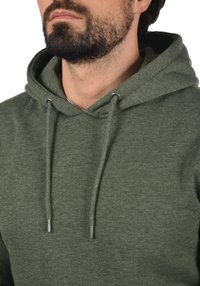 Green hoodie made of soft fabric, featuring a drawstring with metal tips, a front kangaroo pocket, and a relaxed fit.