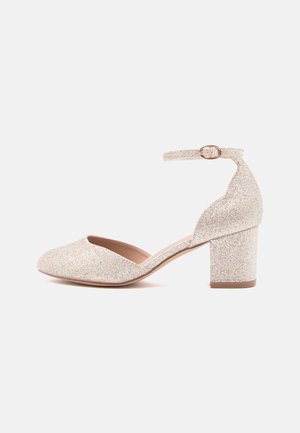 Błyszczące złote buty na szerokim obcasie z paskiem wokół kostki, otwartym noskiem i gładką podszewką. Teksturowana powierzchnia dodaje iskierkowego detalu.