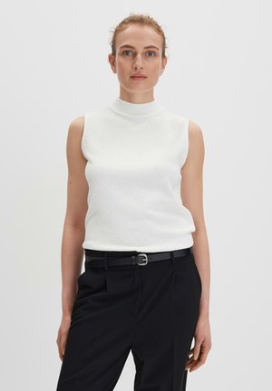 Haut sans manches blanc avec un col haut, fabriqué à partir d'un tissu texturé. Associé à un pantalon noir et une ceinture noire slim avec une boucle en argent.