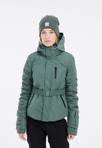 Groene geïsoleerde jas met een ritssluiting aan de voorkant, verstelbare capuchon en een ceintuur op de taille. Voorzien van ritszakken en gegatherde mouwen.