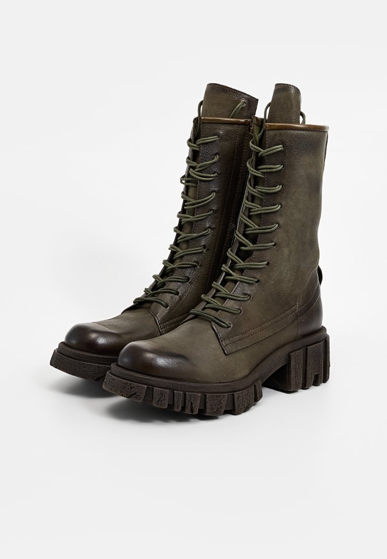 Bottes de combat en cuir vert olive avec une tige haute, un design de laçage prononcé et une semelle épaisse et texturée. Accentuées par une fermeture éclair.