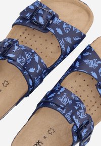 Infradito blu navy con due fibbie regolabili, caratterizzati da un motivo di pesci in azzurro chiaro, con una soletta in sughero testurizzato e fori di ventilazione.