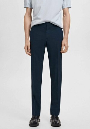 Pantaloni tailor cu croi drept, din stofă netedă, cu detalii de pliuri frontale și bucle pentru curea, asociați cu un top cu mânecă scurtă de un albastru deschis.