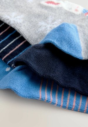 Verschiedene Socken in Grau, Blau, Marineblau und Hellblau mit unterschiedlichen Mustern, einschließlich Streifen und Schneeflocken. Weiche Stricktextur und glatte Oberfläche.