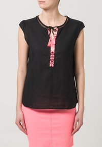 Schwarzes kurzärmeliges Oberteil mit strukturiertem Finish, das eine rosa gemusterte vertikale Passe und Quastenakzente am Ausschnitt aufweist.
