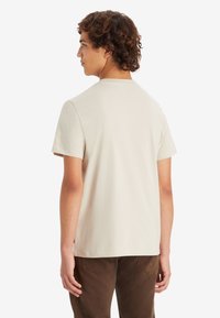 Camiseta de manga corta y cuello redondo en algodón beige claro, con un diseño sencillo, un ajuste relajado y sin patrones ni acentos visibles.