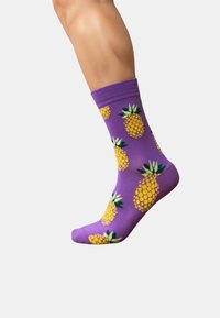 Fioletowa bawełniana skarpeta z żółtymi wzorami ananasa z zielonymi akcentami, ściągaczem i gładką teksturą.