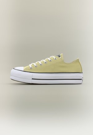 Niedriger, hellgrüner Canvas-Sneaker mit weißer Gummisohle, Zehenkappe und Schnürsenkeln, seitlich auf neutralem Hintergrund gezeigt.