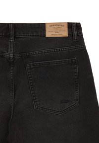 Jeans in denim nero con un'etichetta in pelle in vita. Presentano una tasca sul retro e dettagli di cuciture sottili. Tessuto di alta qualità.