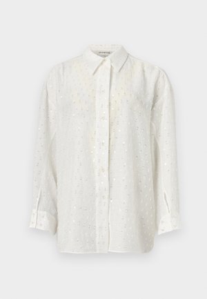 Λευκό πουκάμισο με κουμπιά από ελαφρύ ύφασμα, με διακριτικό υφή και μικρές αντανακλαστικές παγιέτες σε όλο το ύφασμα. Μακριά μανίκια με μανσέτες.