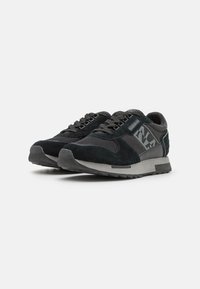 Baskets de sport noires en mélange de daim et de mesh, avec une semelle grise et des accents géométriques sur les côtés.
