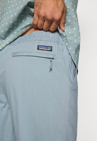 Ανοιχτό μπλε σορτς φτιαγμένο από απαλό ύφασμα, με ελαστική μέση, πίσω τσέπη με φερμουάρ και κεντημένη ετικέτα Patagonia στη μέση.