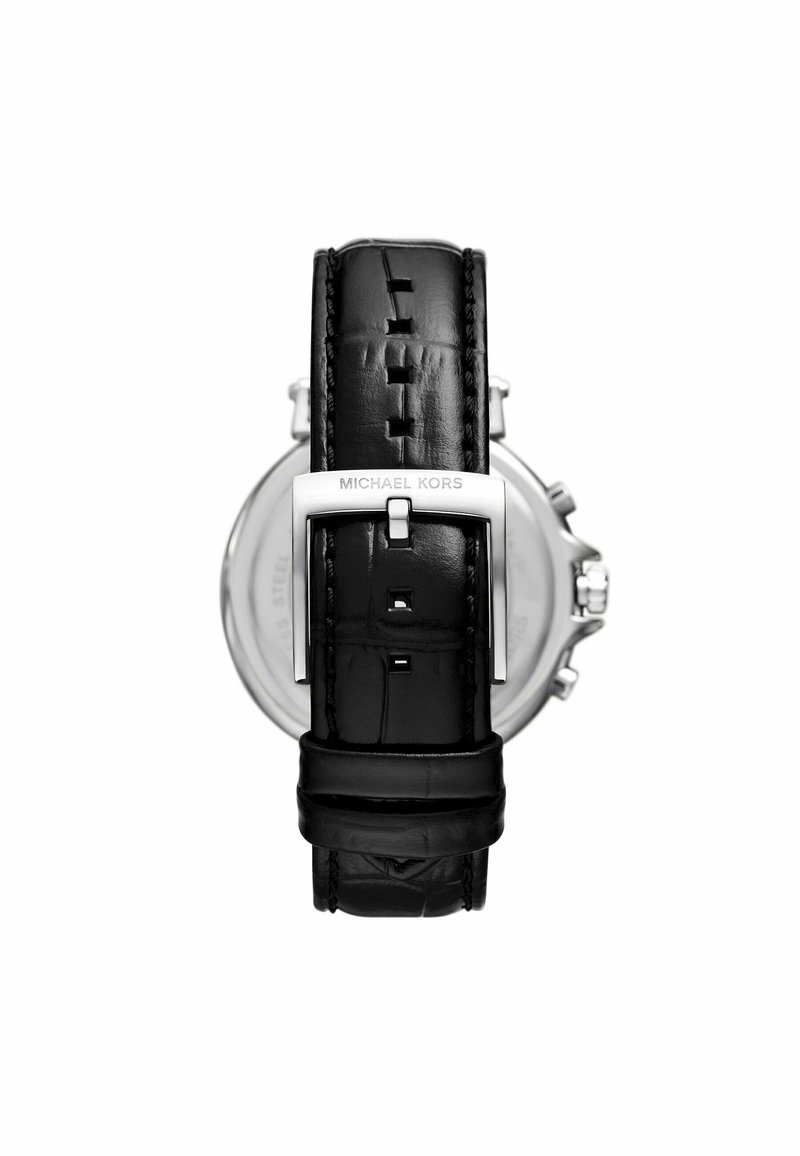Correa de reloj de cuero negro con hebilla de plata grabada "Michael Kors," unida a la parte trasera de un reloj cronógrafo plateado sobre un fondo blanco.